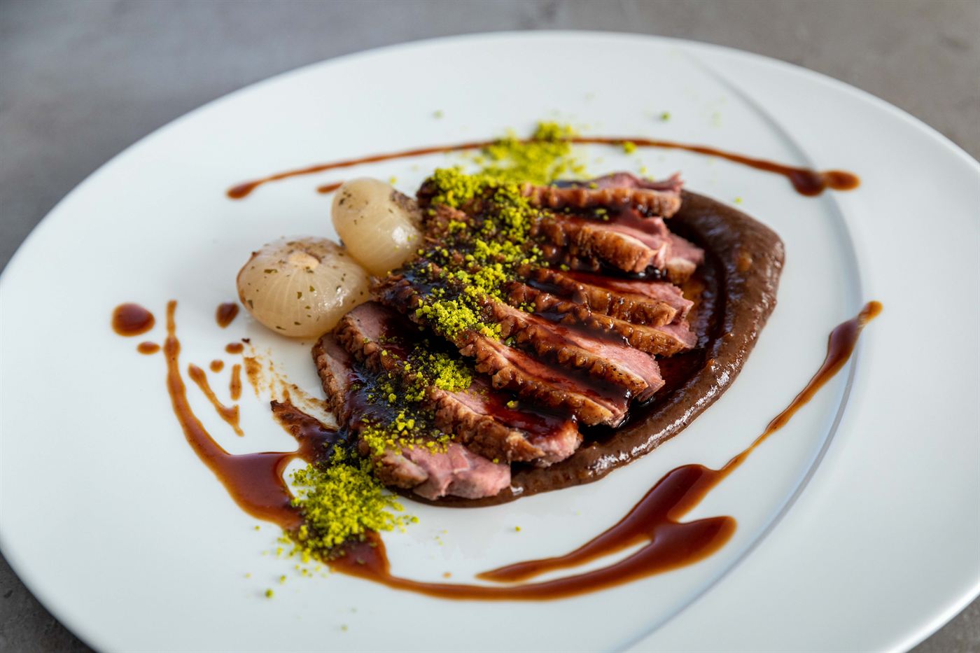Sliced duck breast with pistachio and onion