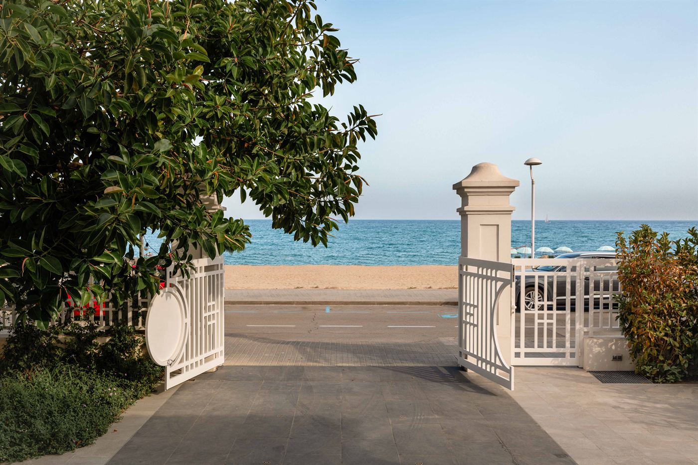 The hotel gate opening onto the seafront promenade, with the beach and sea beyond